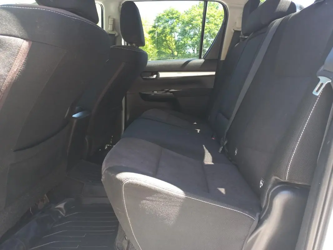 Vue intérieure côté droit sur la banquette arrière noire du Toyota Hilux 4x4 double cabine, avec ceinture de sécurité visible.