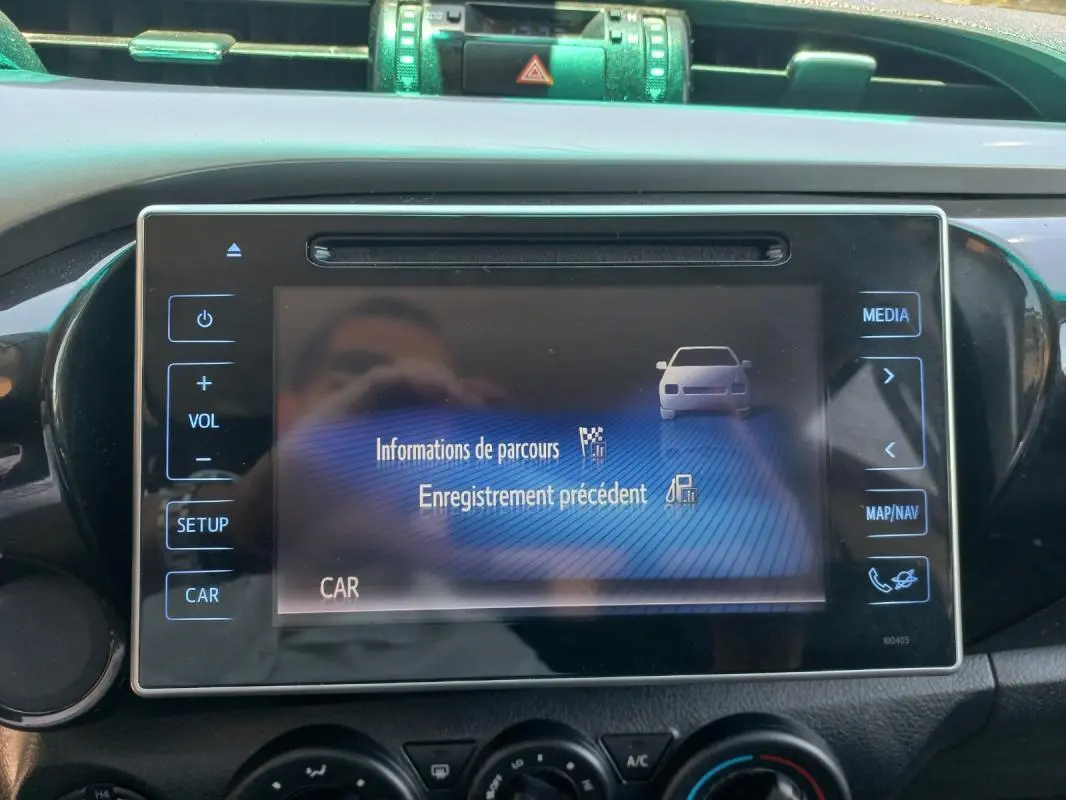 Écran tactile central du Toyota Hilux 2018 affichant les informations de parcours, avec commandes autour en vue frontale.