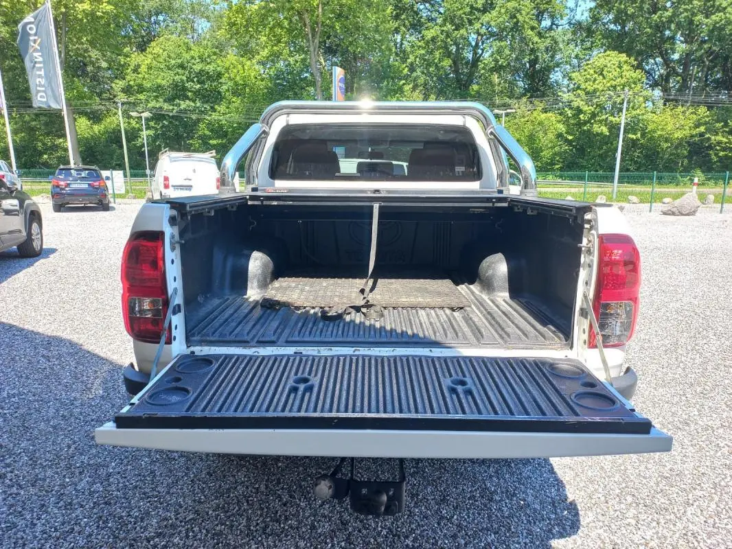 Vue arrière d’un Toyota Hilux 4x4 blanc de 2018 avec benne ouverte et intérieur de caisse visible.