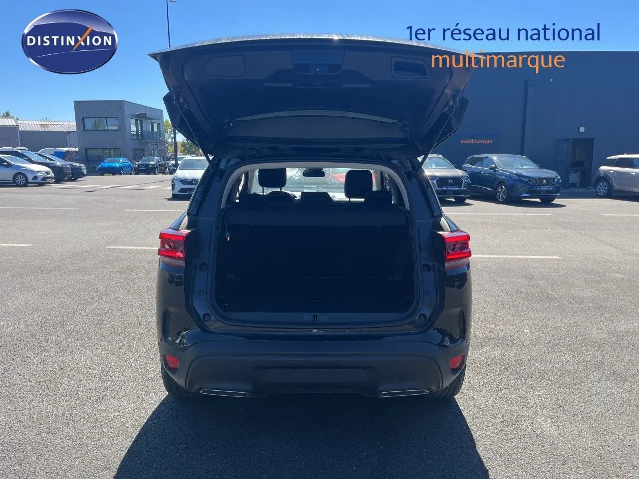 Vue arrière d'un Citroën C5 Aircross noir métal 2025 avec coffre ouvert sur parking extérieur.