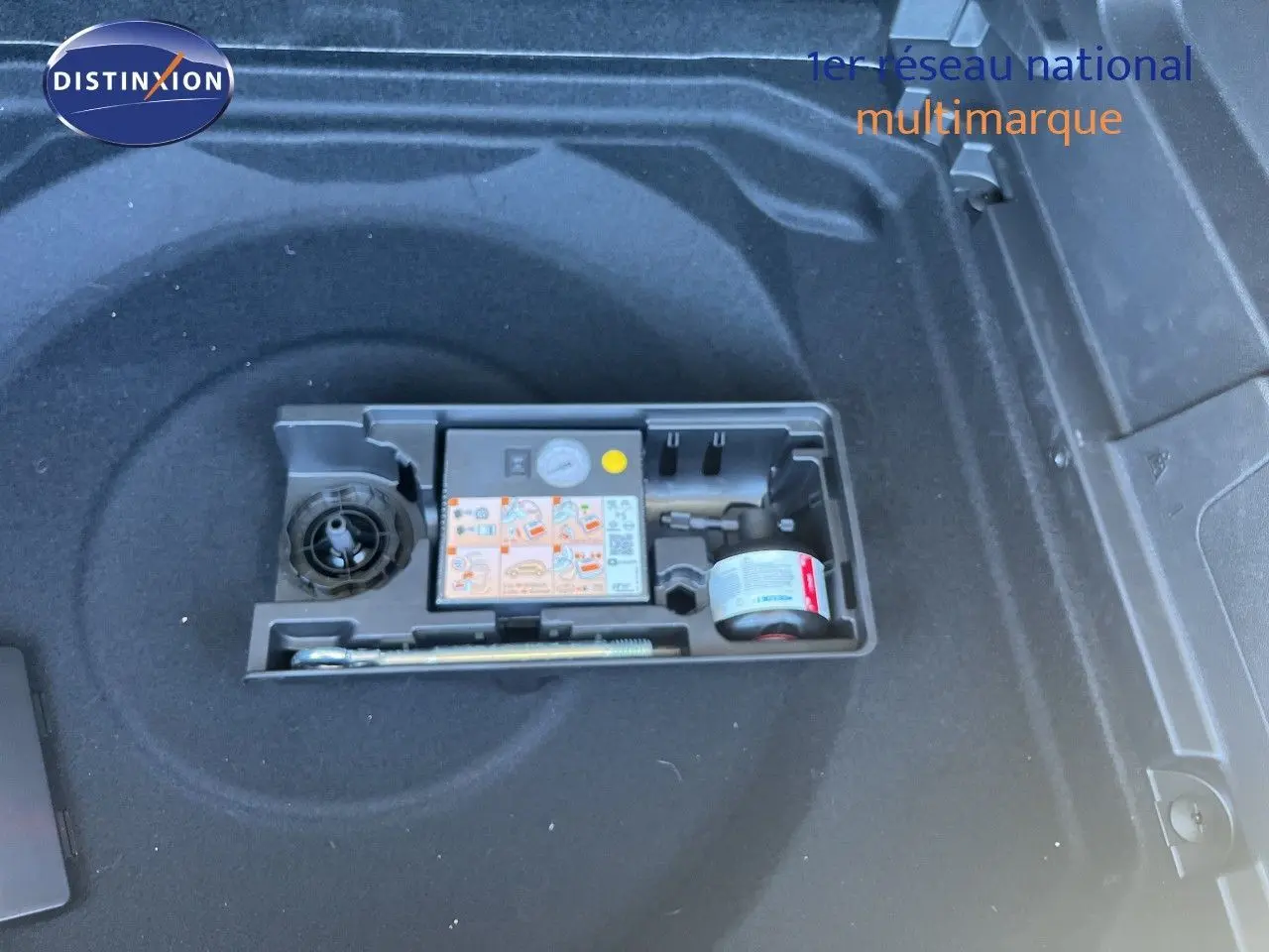 Compartiment de coffre avec kit de réparation pneus dans un Citroën C5 Aircross noir métal, vue plongeante.