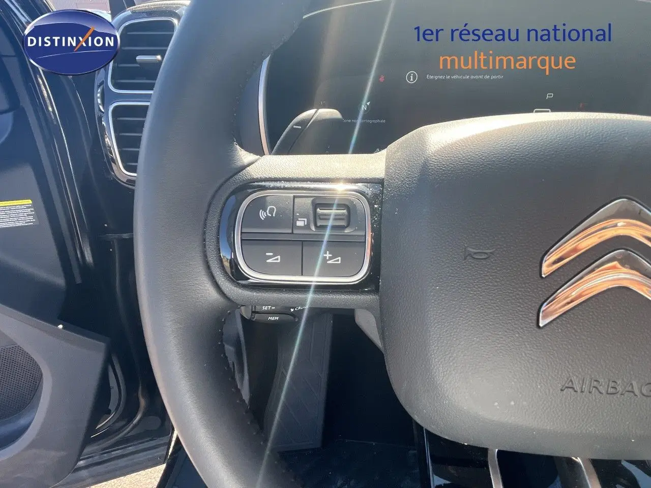 Gros plan sur le volant cuir noir du Citroën C5 Aircross 2025, avec commandes intégrées et logo chromé visible.