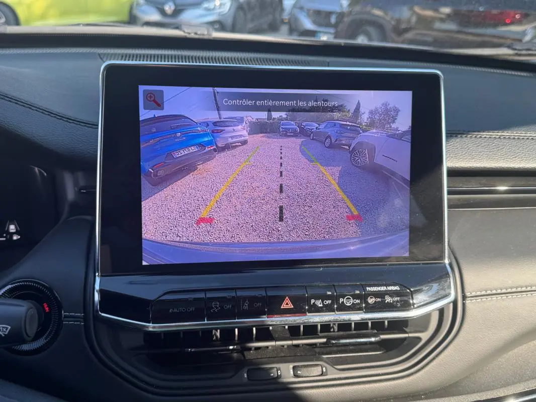 Vue intérieure sur l’écran tactile affichant la caméra de recul du Jeep Compass bleu, avec tableau de bord noir et commandes visibles.
