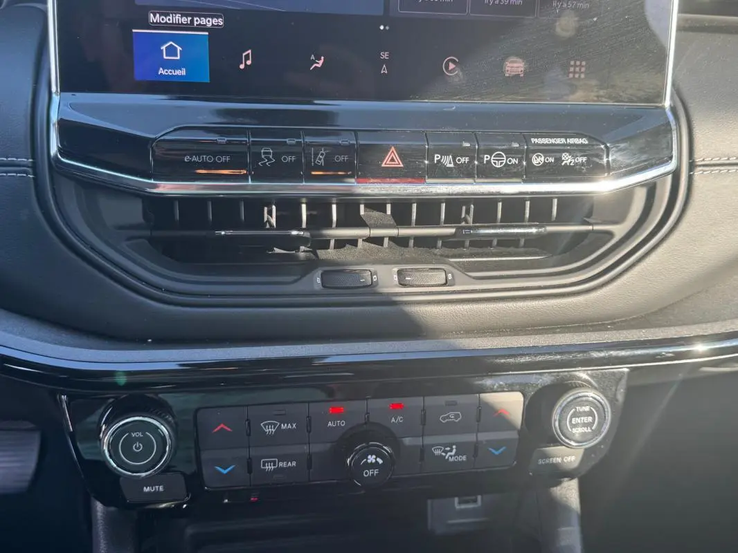 Gros plan sur la console centrale du Jeep Compass bleu 2025, montrant les commandes climatisation et écran tactile.