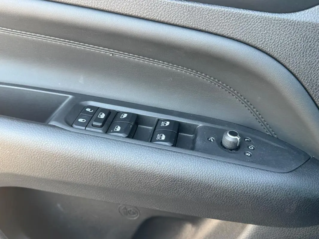 Gros plan sur la commande des vitres et rétroviseurs côté conducteur du Jeep Compass 2025, intérieur noir.