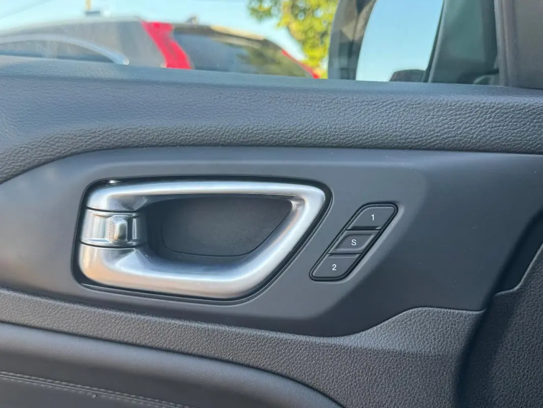 Poignée intérieure côté gauche en métal brossé avec boutons de mémorisation des sièges sur Jeep Compass bleu 2025.