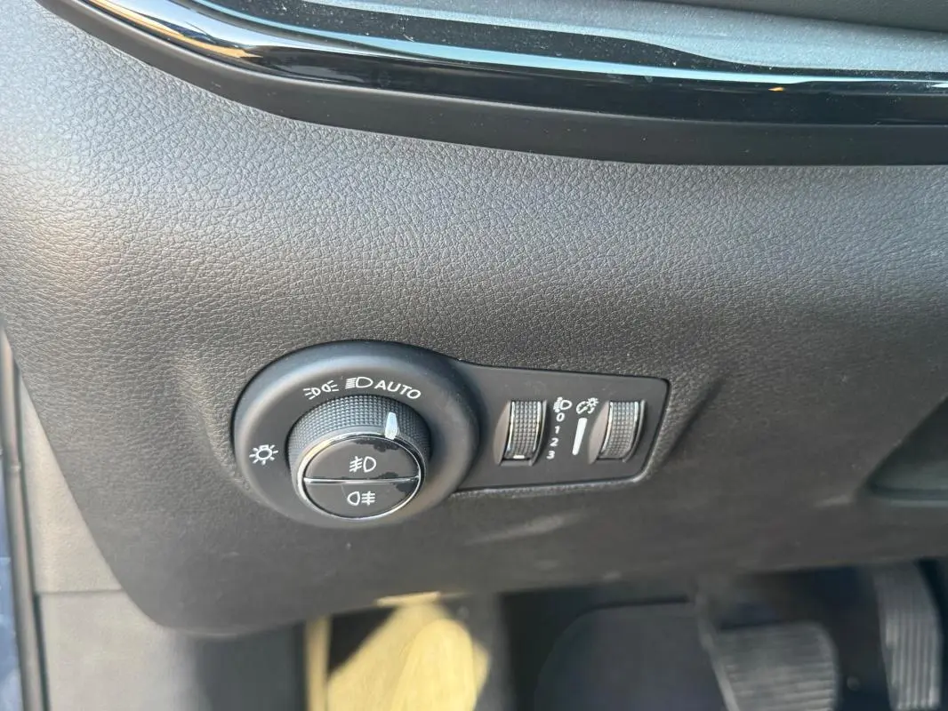 Gros plan sur le tableau de bord noir du Jeep Compass 2025, montrant les commandes d’éclairage et réglages des phares.