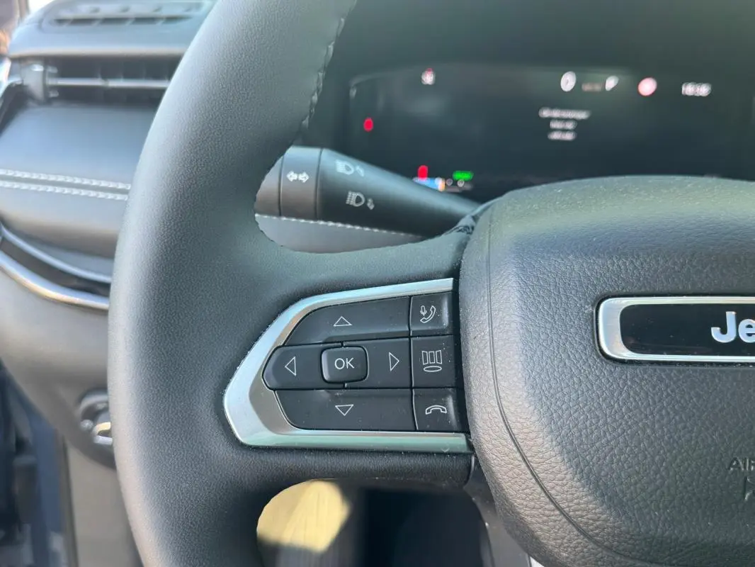 Gros plan sur le volant noir du Jeep Compass 2025 avec commandes intégrées et logo Jeep visible.