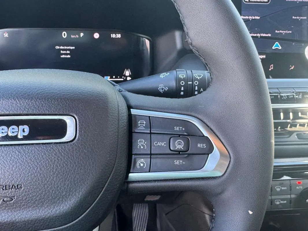 Gros plan sur le volant côté droit du Jeep Compass bleu 2025 avec commandes de régulateur de vitesse et tableau de bord digital.