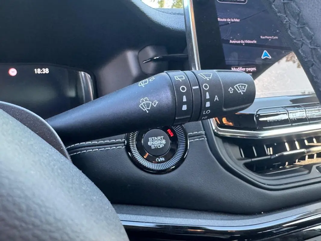 Gros plan intérieur sur la commande des essuie-glaces et le bouton start/stop du Jeep Compass bleu 2025, avec écran tactile visible.