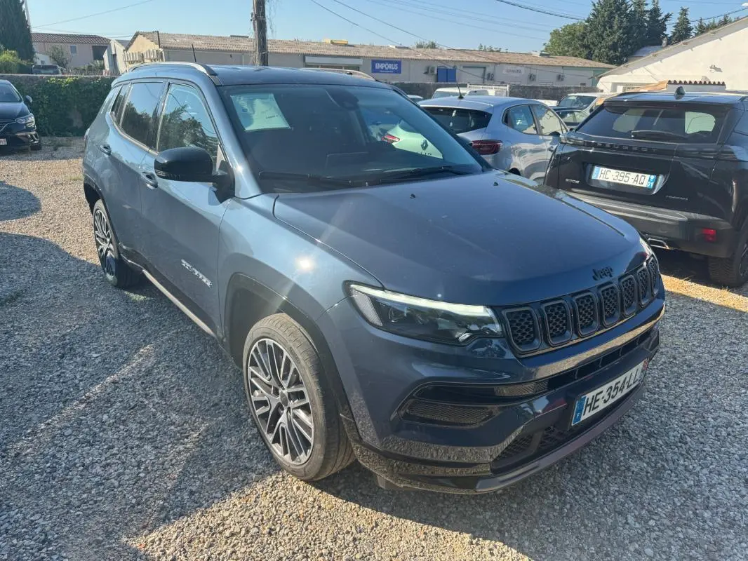 Jeep Compass bleu en 3/4 avant droit, avec jantes alliage 19 pouces et barres de toit visibles.