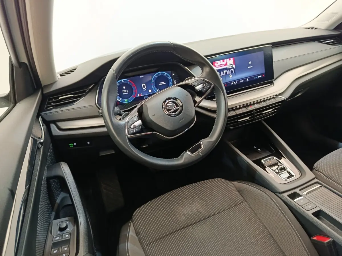 Vue intérieure côté conducteur de la Skoda Octavia 2023, volant cuir multifonctions et écran tactile central lumineux.
