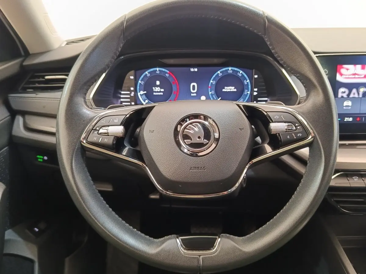 Vue rapprochée du volant cuir et alu multifonctions de la Skoda Octavia 2023 avec tableau de bord numérique éclairé.