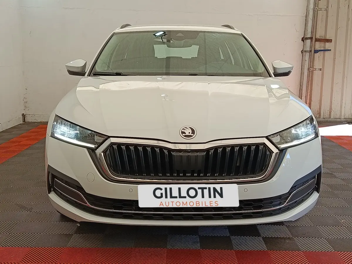Vue frontale d'une Skoda Octavia blanche 2023 avec phares LED allumés et calandre noire distinctive.