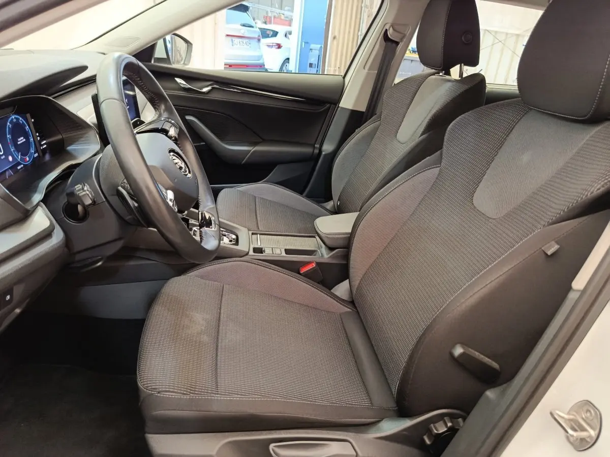 Intérieur de la Skoda Octavia blanc, vue côté conducteur, volant cuir alu multifonctions et sièges tissu gris.