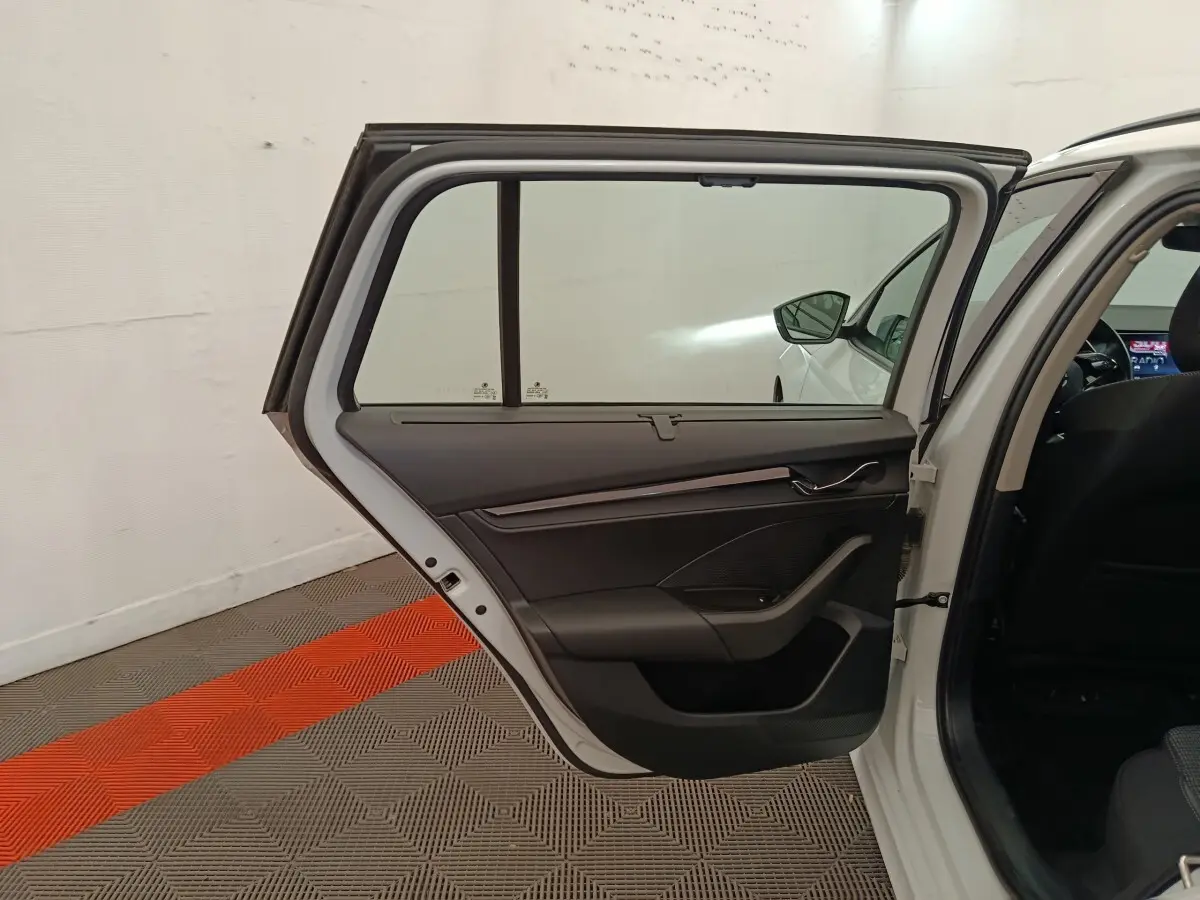 Porte arrière gauche ouverte d'une Skoda Octavia blanche, intérieur noir avec détails modernes et vitre teintée.