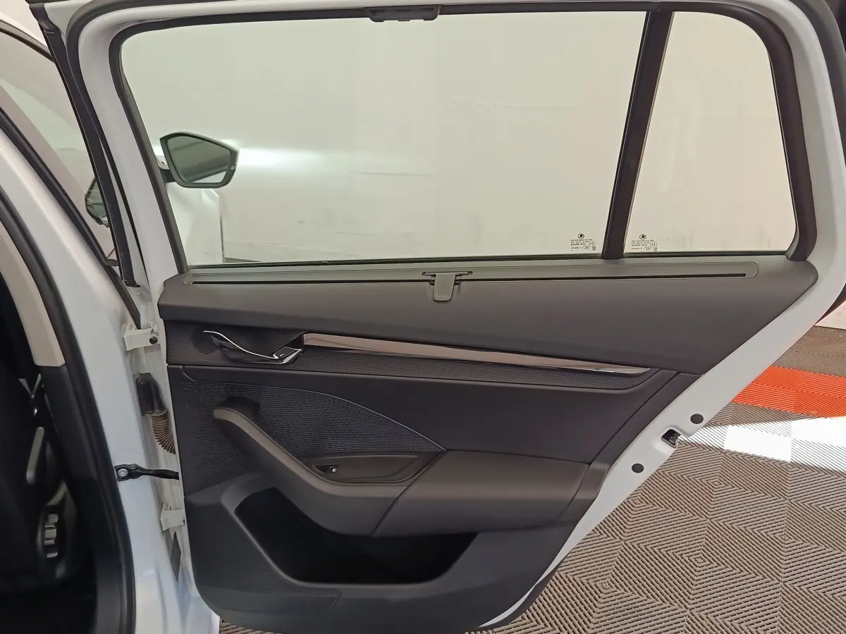 Vue intérieure de la porte arrière gauche blanche d'une Skoda Octavia 2023 avec garniture noire et poignée chromée.