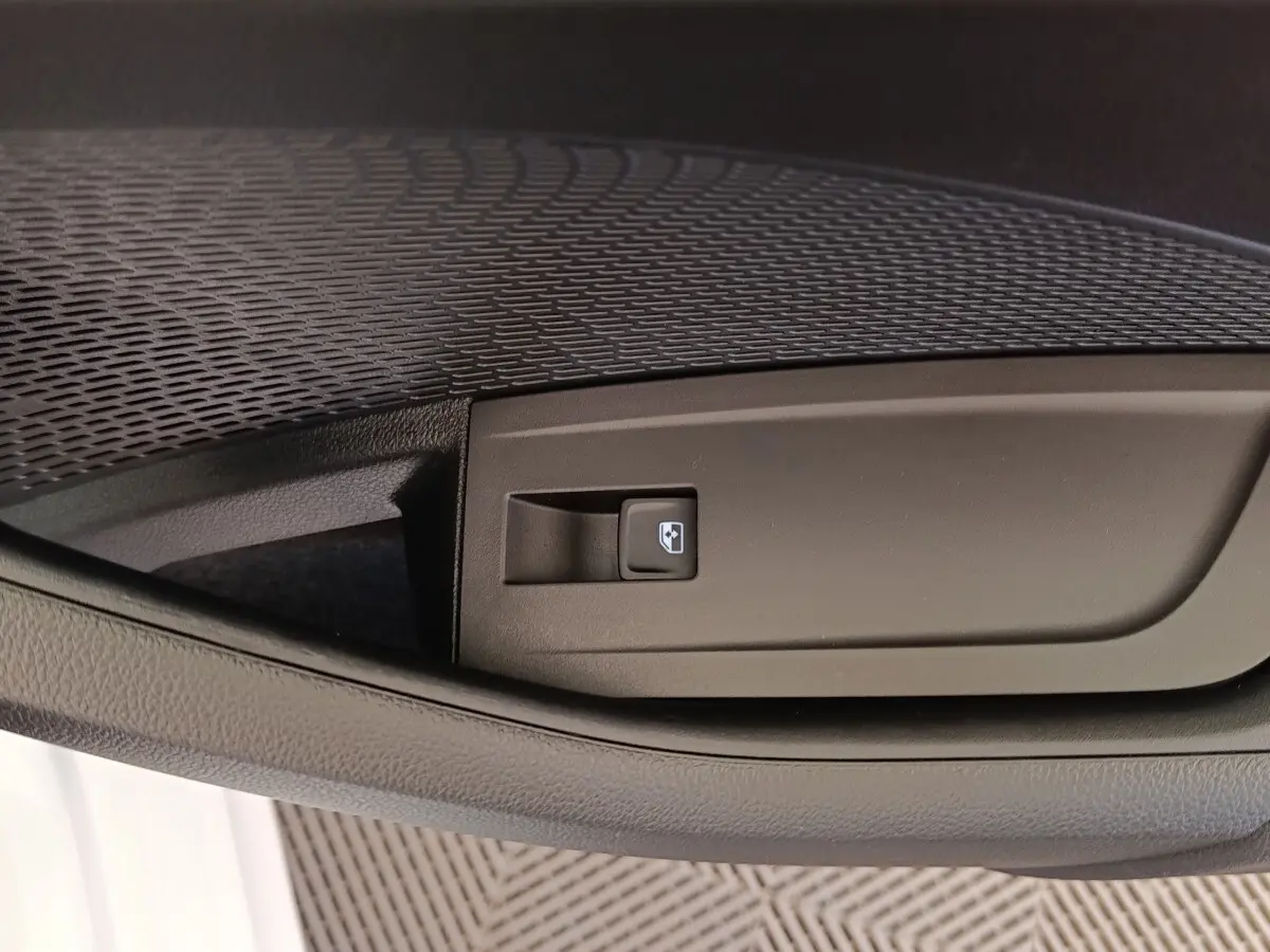 Gros plan sur le bouton de commande de la vitre électrique côté conducteur de la Skoda Octavia blanche 2023.