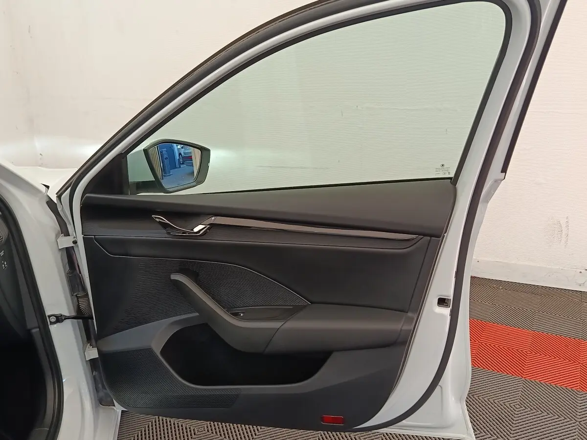 Vue intérieure de la porte avant gauche d'une Skoda Octavia blanche, avec garniture noire et poignée chromée.