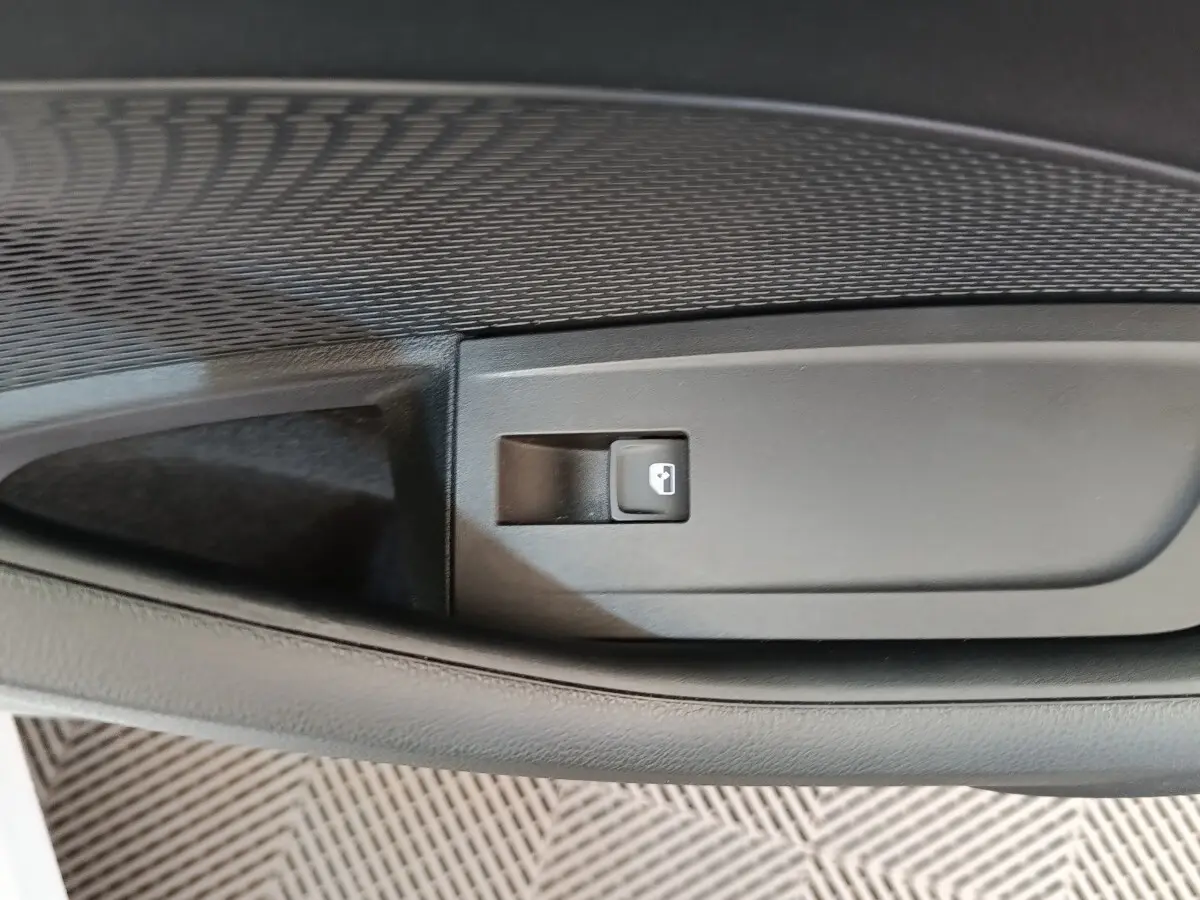 Gros plan sur le bouton d’ouverture de coffre intégré dans la garniture intérieure noire d’une Skoda Octavia 2023.