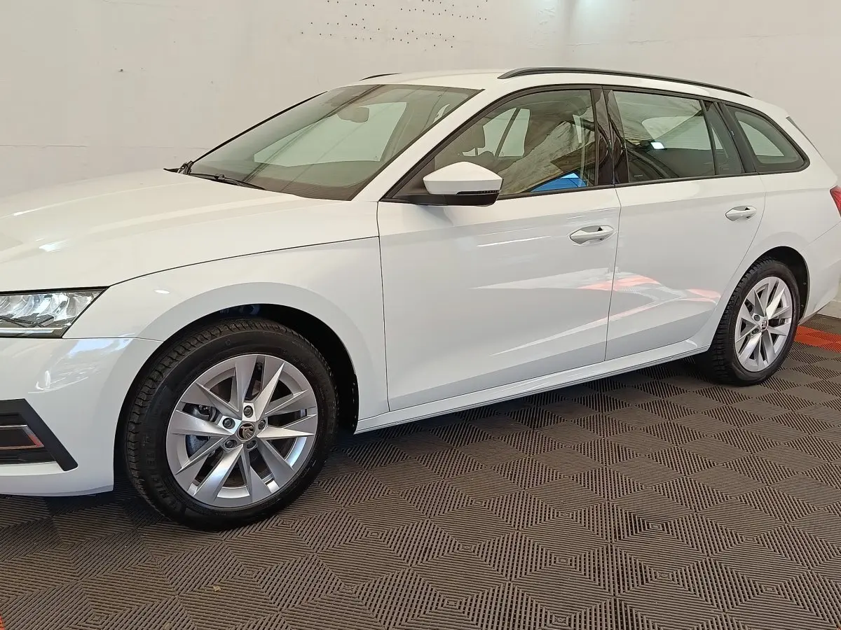 Vue de profil côté gauche d'une Skoda Octavia break blanche 2023 avec jantes alliage et rétroviseurs blancs.