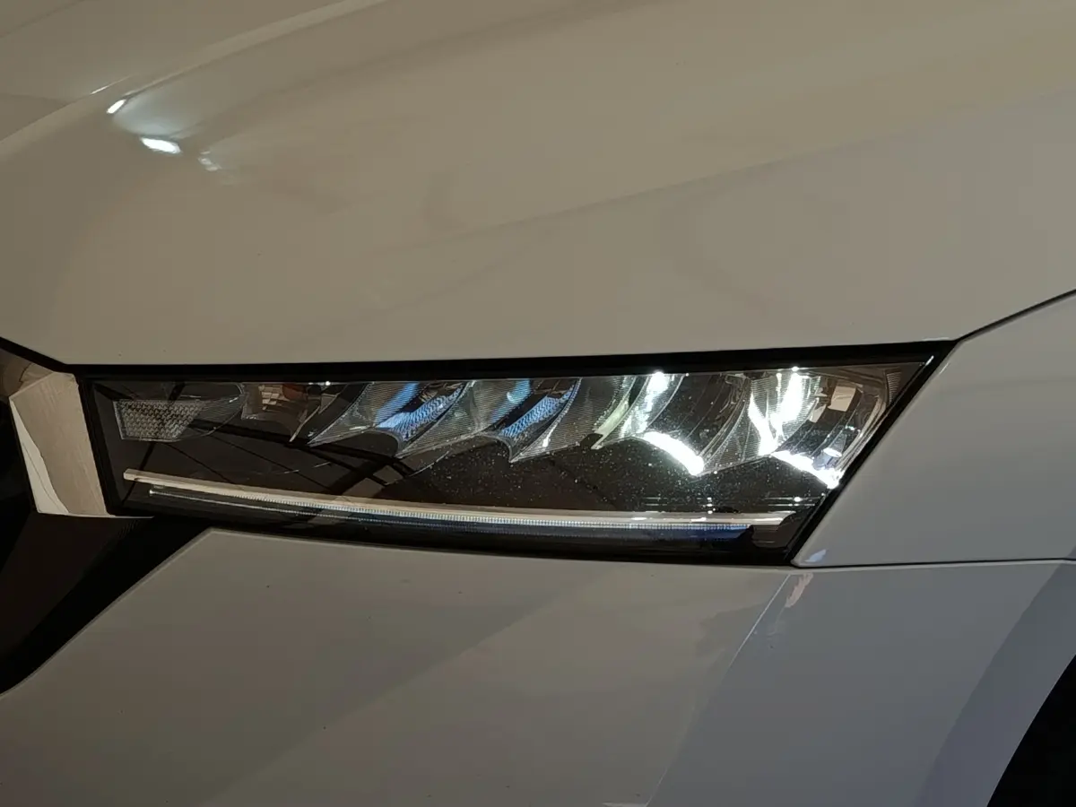 Gros plan sur le phare avant droit LED d'une Skoda Octavia blanche 2023, soulignant son design moderne et précis.