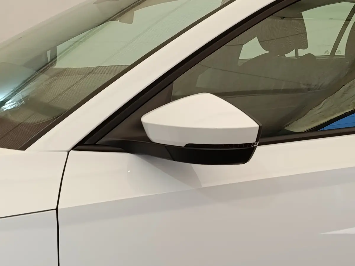 Vue rapprochée du rétroviseur côté conducteur d’une Skoda Octavia blanche 2023 avec vitre teintée.