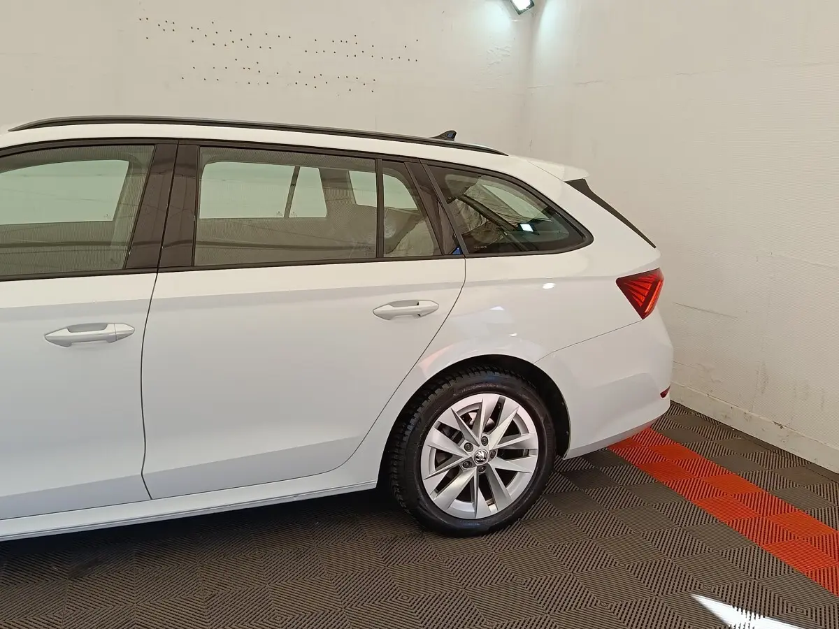 Vue latérale droite d'une Skoda Octavia break blanche 2023, mettant en valeur la roue arrière et les vitres teintées.