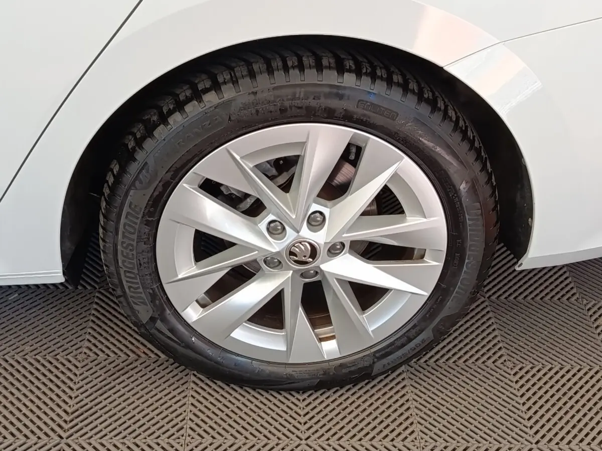 Gros plan sur la roue avant droite d'une Skoda Octavia blanche, mettant en valeur la jante alu à dix branches.