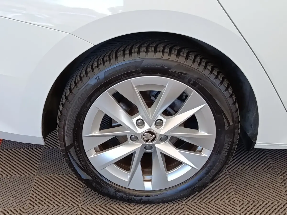 Gros plan sur la roue avant droite d'une Skoda Octavia blanche, avec jante alliage à dix branches.