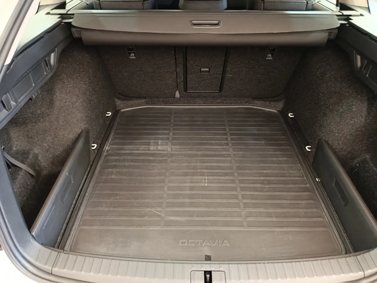 Vue plongeante sur le coffre spacieux noir de la Skoda Octavia 2023 avec tapis de sol marqué Octavia.