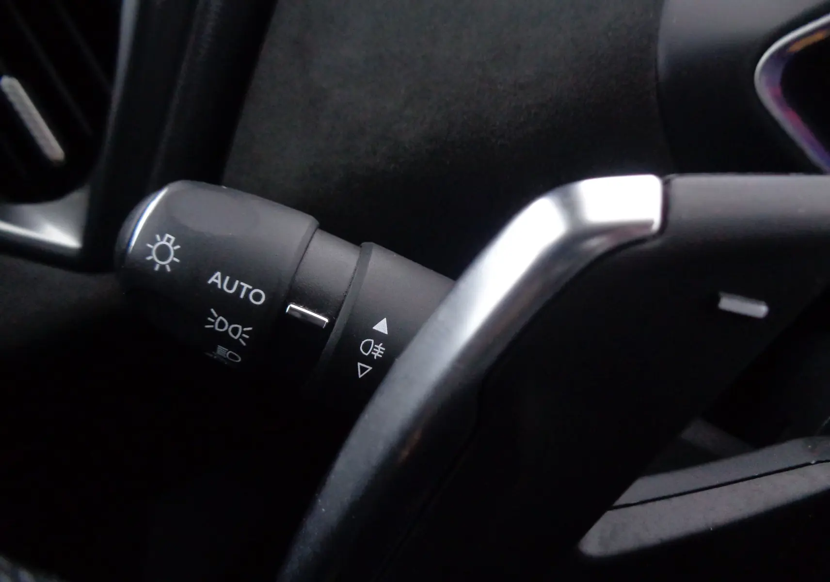 Gros plan sur la manette de feux automatique à gauche du volant dans l'habitacle noir du DS3 Crossback blanc banquise.