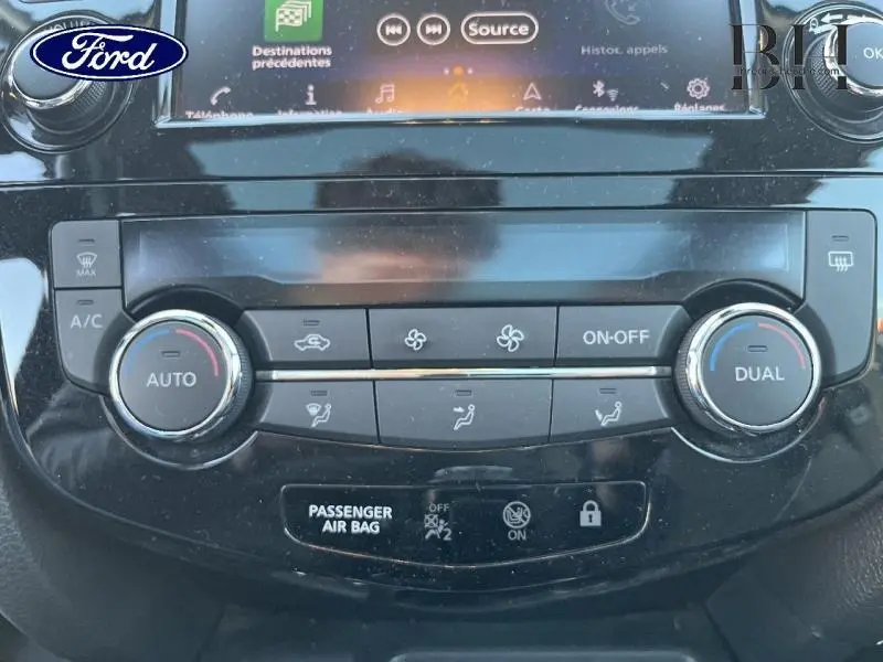 Vue rapprochée de la console centrale noire du Nissan Qashqai 2019, mettant en valeur les commandes de climatisation bi-zone.