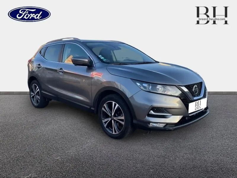 Nissan Qashqai gris Squale en 3/4 avant droit, jantes alu et feux LED visibles sur fond neutre.