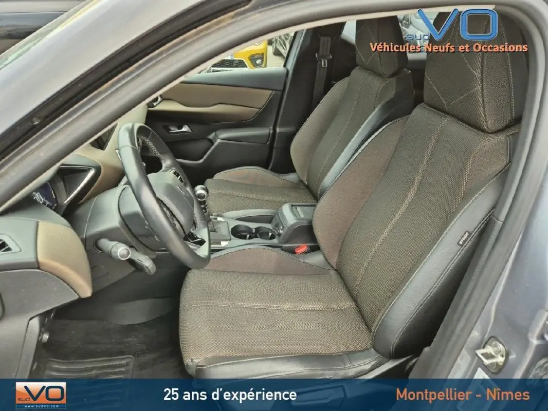 Intérieur avant du DS3 Crossback gris 2020, sièges tissu et cuir, volant multifonction et accoudoir central visible.