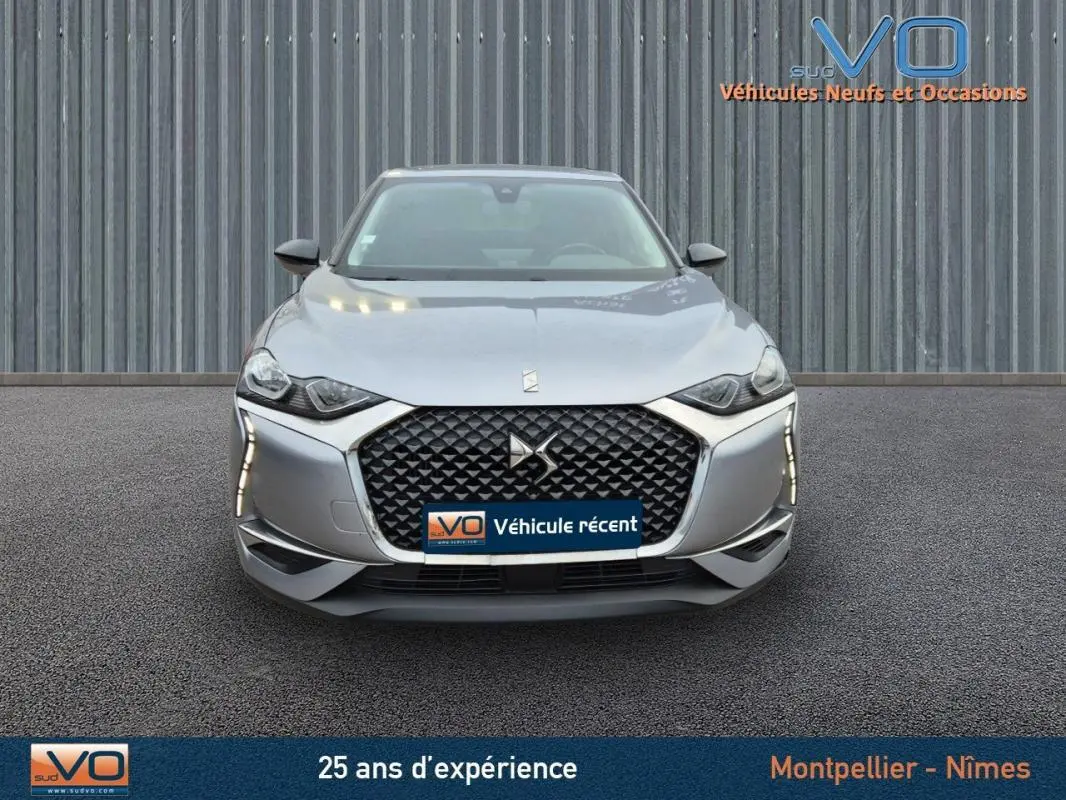 Vue frontale d'une DS3 Crossback gris métallisé avec calandre distinctive et feux diurnes LED verticaux.