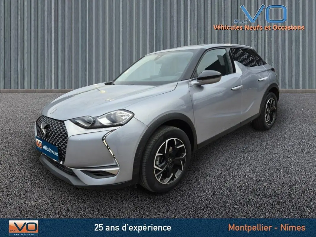Vue 3/4 avant d'un DS3 Crossback gris avec jantes alliage 17 pouces sur fond neutre industriel.