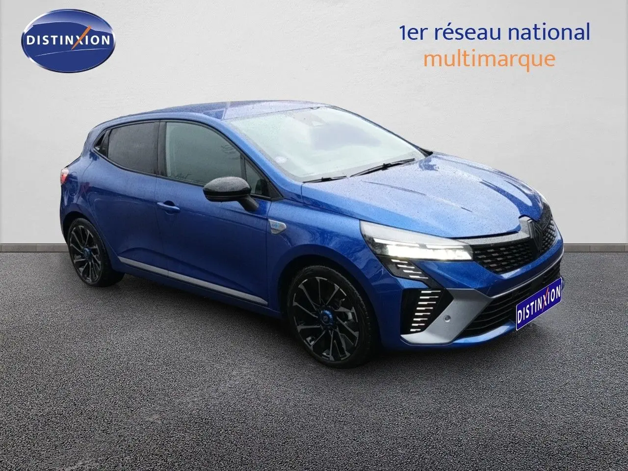 Renault Clio 1.6 E-TECH 145ch hybride bleu Iron Metal vue 3/4 avant droit avec jantes noires et feux allumés.