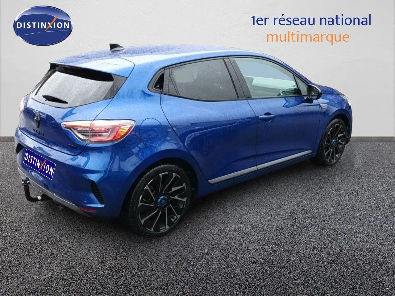 Renault Clio 1.6 E-Tech hybride bleu Iron Metal vue 3/4 arrière côté droit avec jantes noires distinctives.