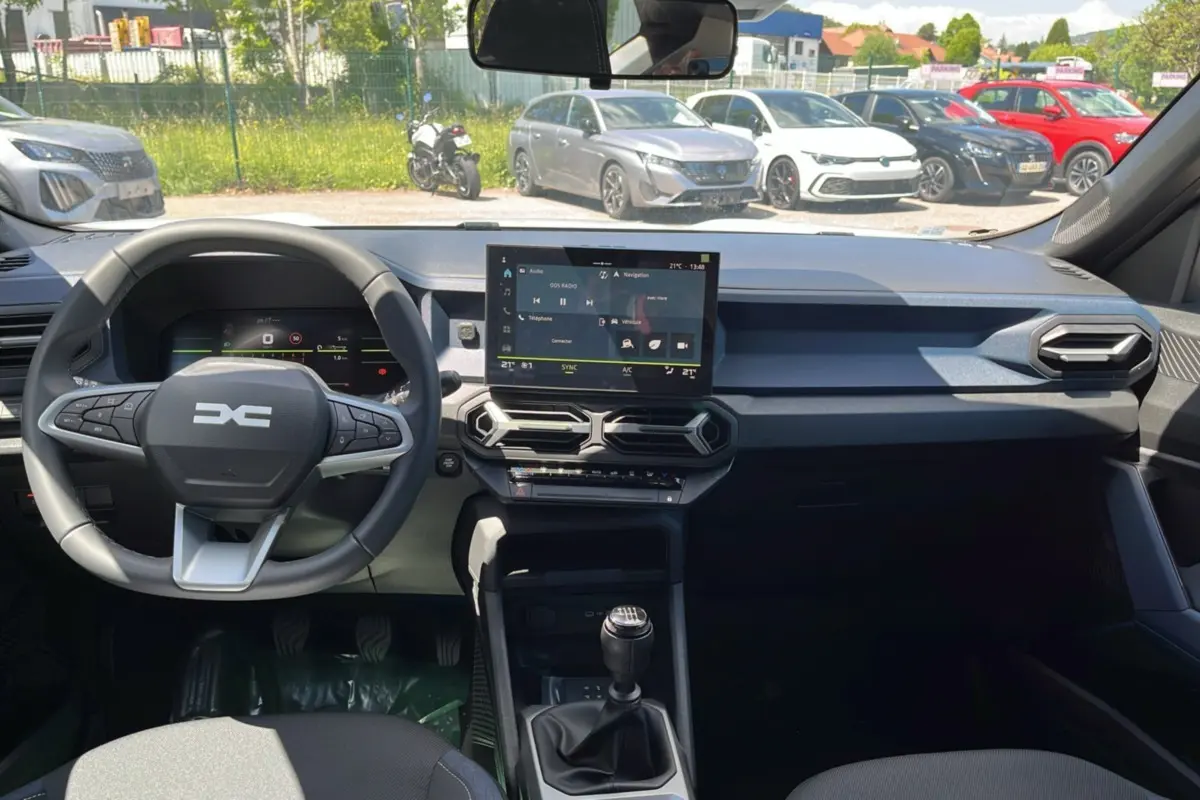 Vue intérieure du tableau de bord et volant du Dacia Bigster blanc glacier 2025, avec écran tactile central et boîte manuelle.