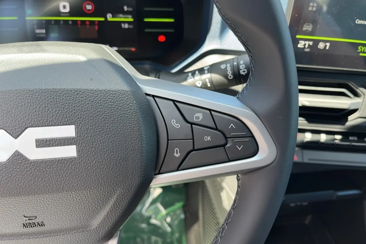 Gros plan sur le volant cuir du Dacia Bigster 2025, montrant les commandes multifonctions côté droit et l'écran digital en arrière-plan.