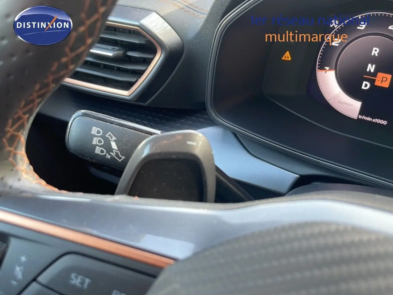 Gros plan sur le tableau de bord et le volant avec surpiqûres orange du CUPRA Formentor 2.0 TDI 150ch blanc neige metal 2025.