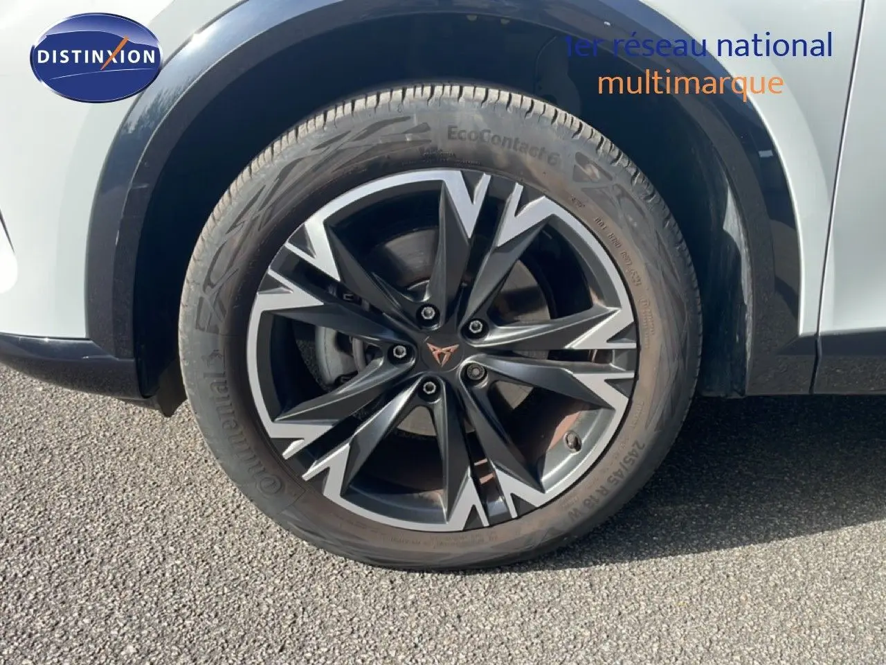 Gros plan sur la roue avant droite du CUPRA Formentor blanc neige métal, avec jante alliage bicolore au design dynamique.