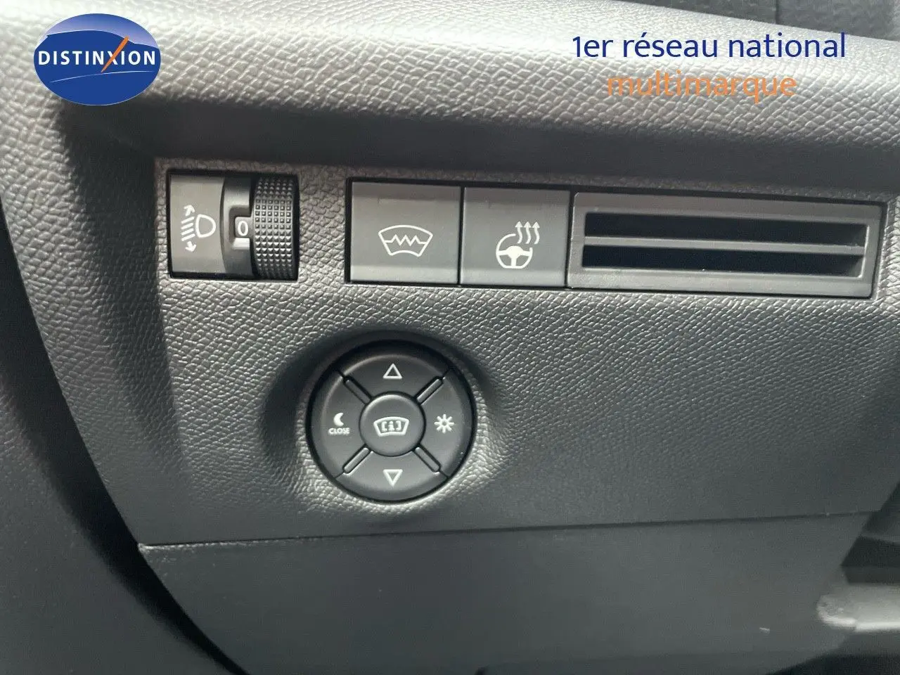 Gros plan sur les commandes de réglage des phares et du volant chauffant dans l'habitacle noir d'une Citroën C4 2024.