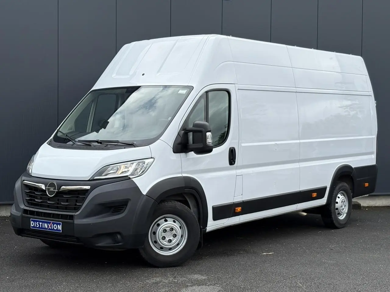 Opel Movano Fourgon blanc vu en 3/4 avant droit, avec pare-chocs noirs et rétroviseurs noirs.