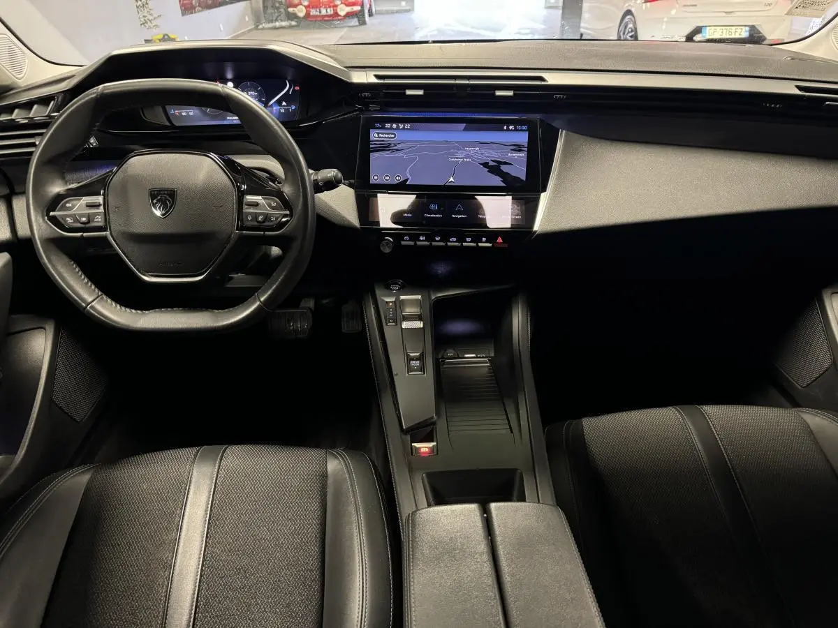 Intérieur avant de la Peugeot 308 SW 2022, tableau de bord noir avec écran tactile central et volant cuir compact.