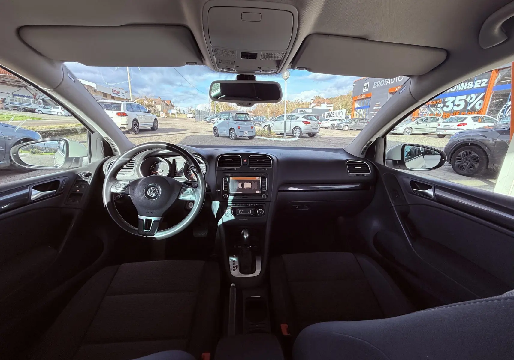 Intérieur noir de la Volkswagen Golf 1.4 TSI 2012 vu de face, avec tableau de bord et volant multifonction visibles.