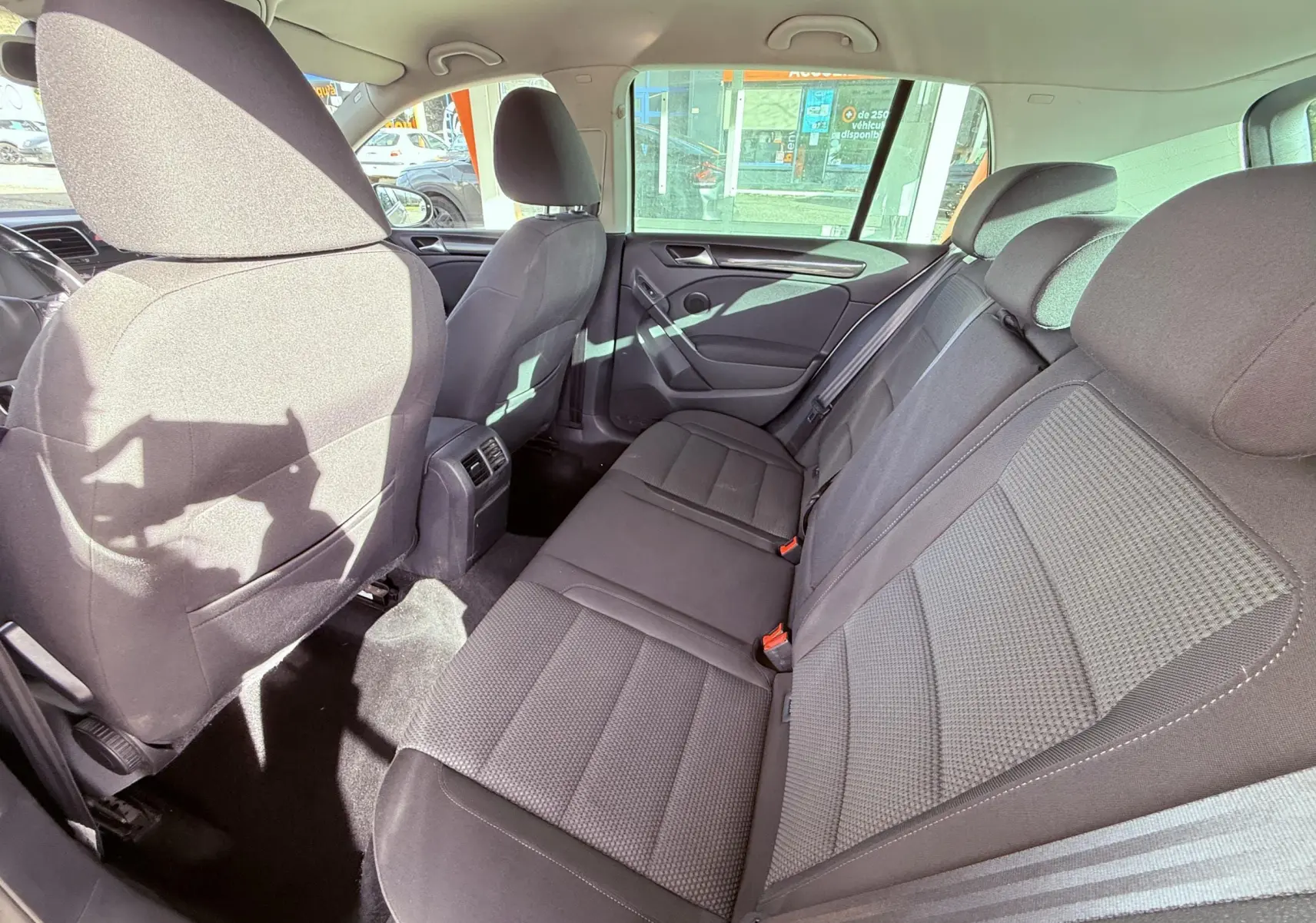 Vue intérieure arrière côté droit de la Volkswagen Golf 1.4 TSI 122 de 2012 avec sièges tissu gris foncé et ceintures visibles.