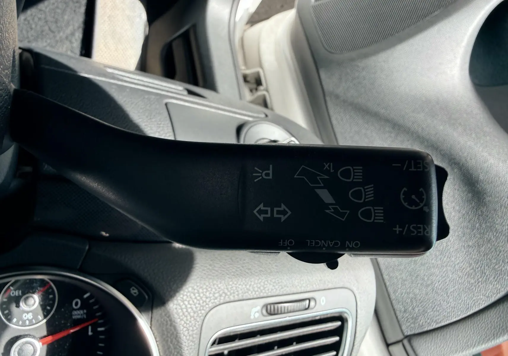 Le levier de clignotant noir de la Volkswagen Golf blanche de 2012, vu de près côté gauche du volant.