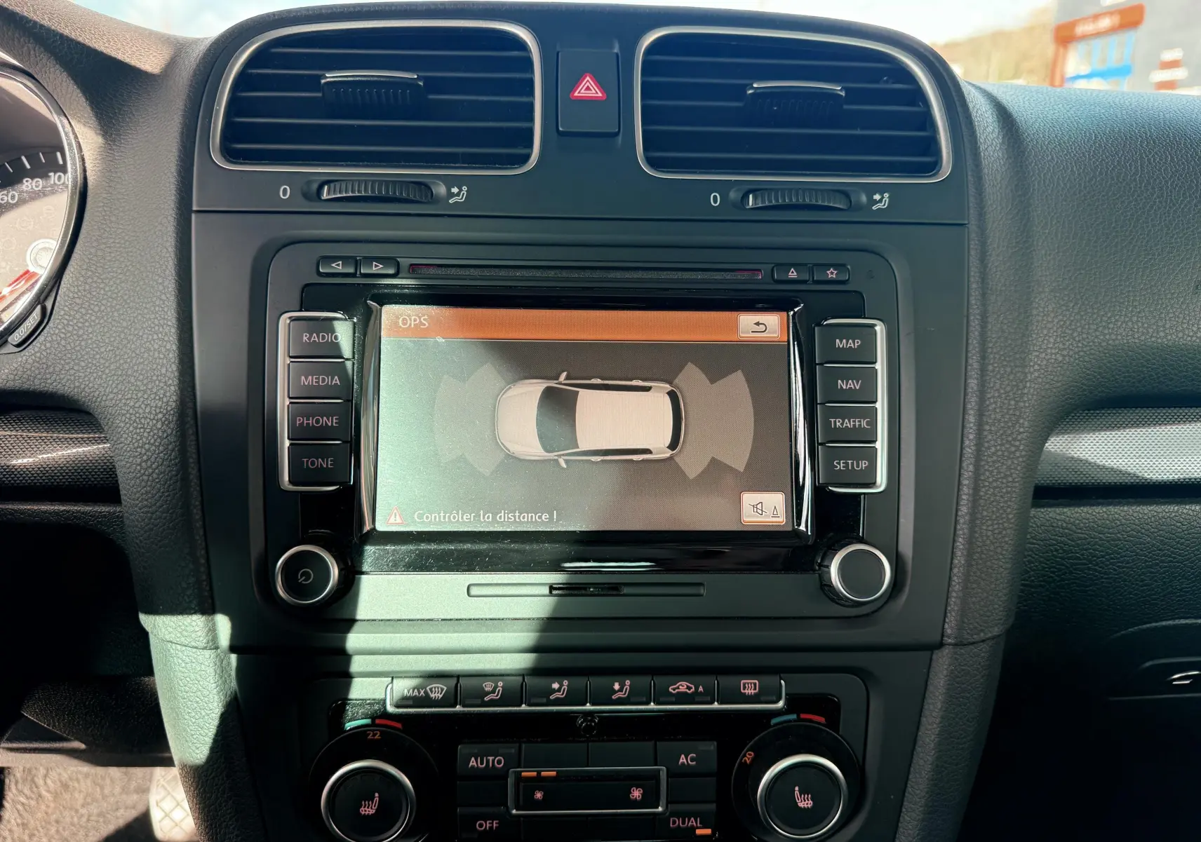 Vue rapprochée du tableau de bord noir de la Volkswagen Golf 1.4 TSI 122 avec écran GPS affichant l'aide au stationnement.